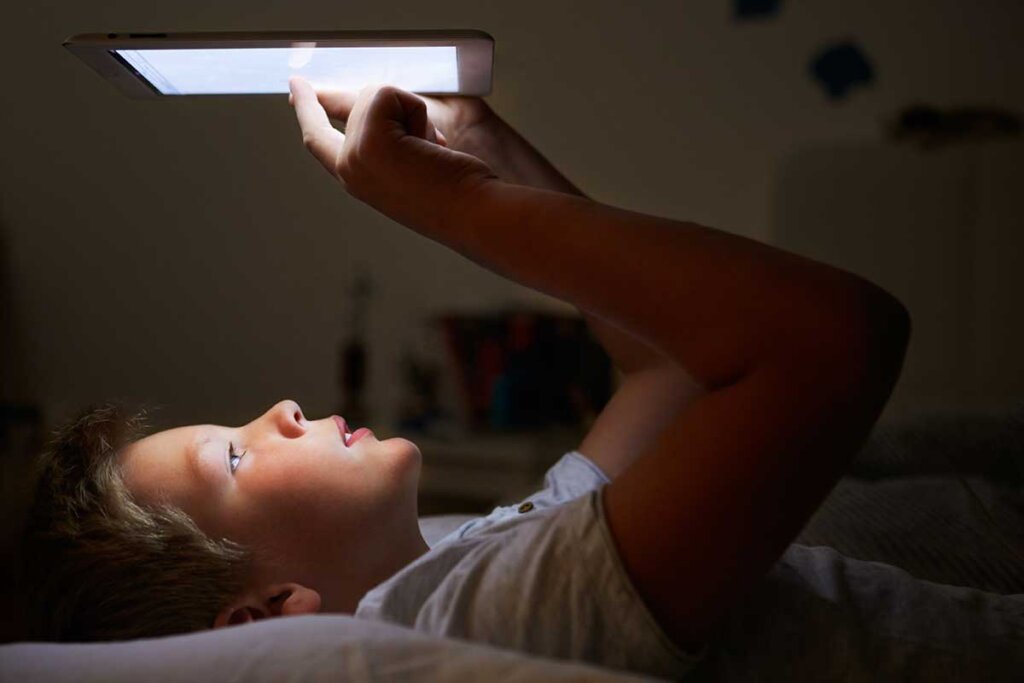 ebook_reader_boy_lieger_i_sängen_och_läser_i_ sin_bok