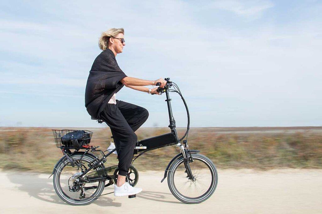 kvinna som cyklar på en hopfällbar elcykel på stranden