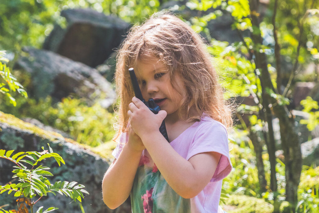 Barn som pratar i en walkie-talkie i skogen.