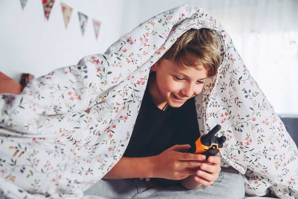 Barn som leker med en walkie-talkie i sängen