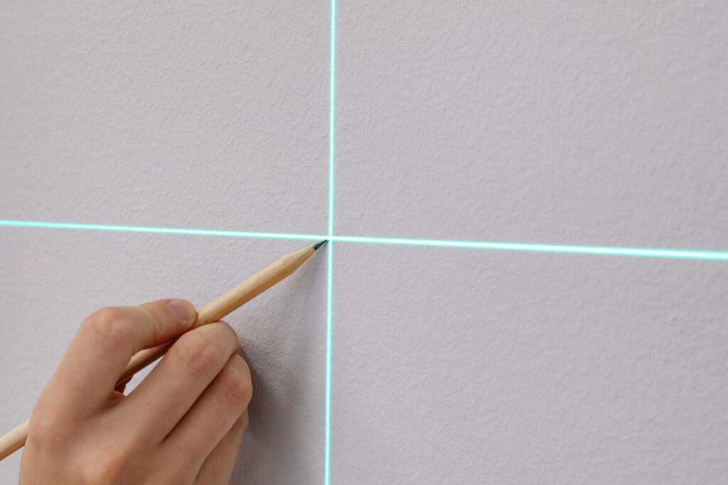 En kvinna markerar en plats med hjälp av en lasernivå.