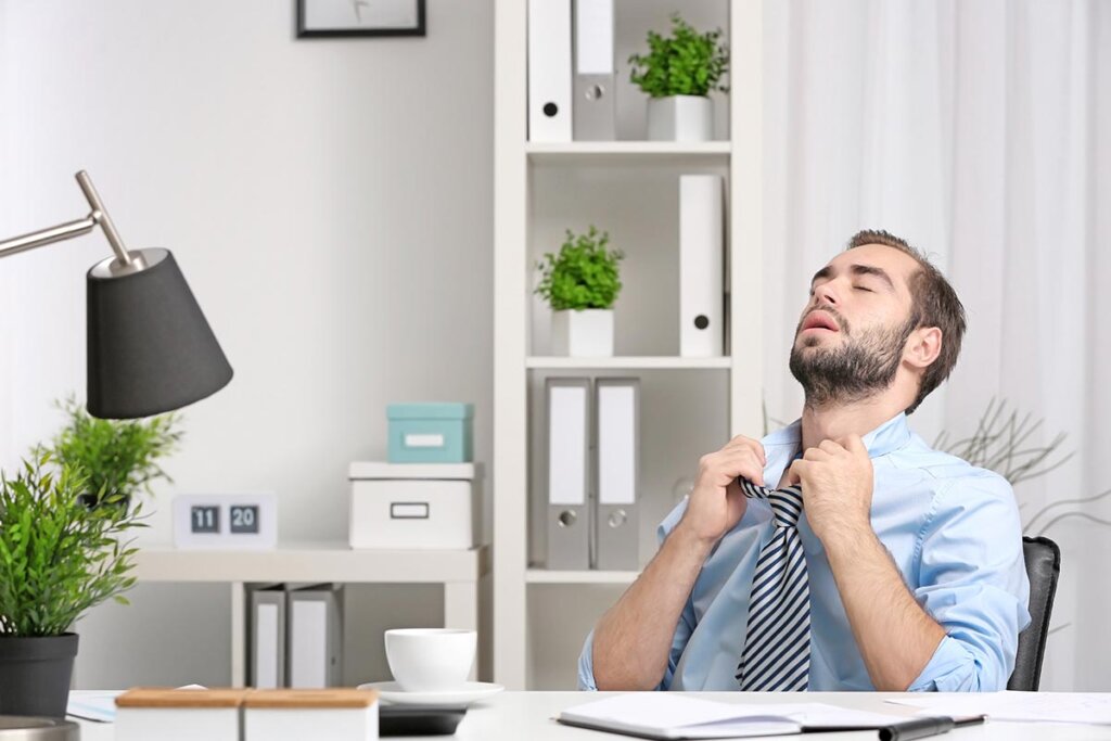 En man som sitter på kontoret och svettas