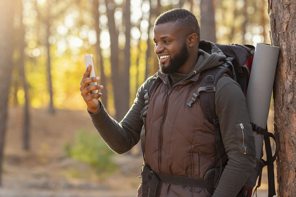 Man i skogen tittar på smartphone