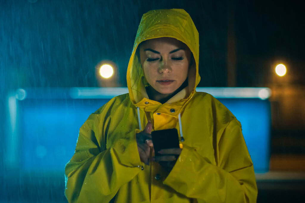 Kvinna i regnet använder smartphone