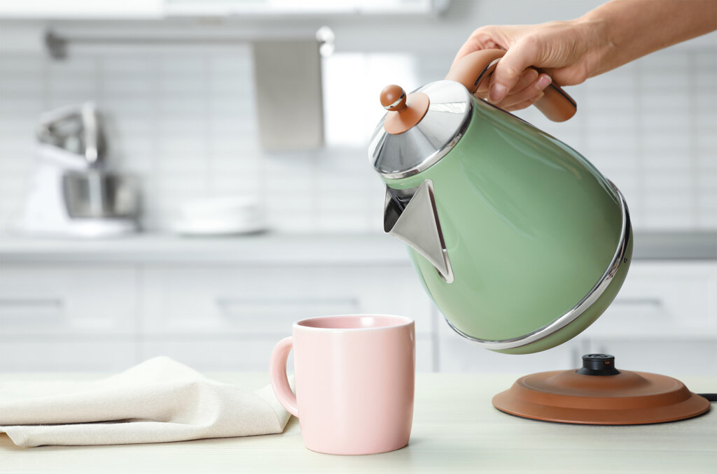 kvinna haller varmt vatten i en mugg