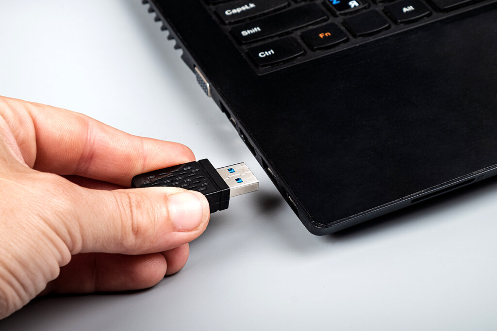 En person sätter in WLAN-pinnen i USB-platsen på den bärbara datorn.
