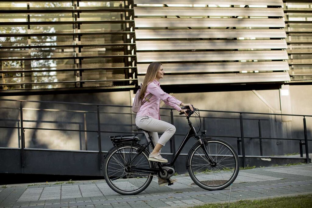 ung kvinna som cyklar på elcykel genom staden